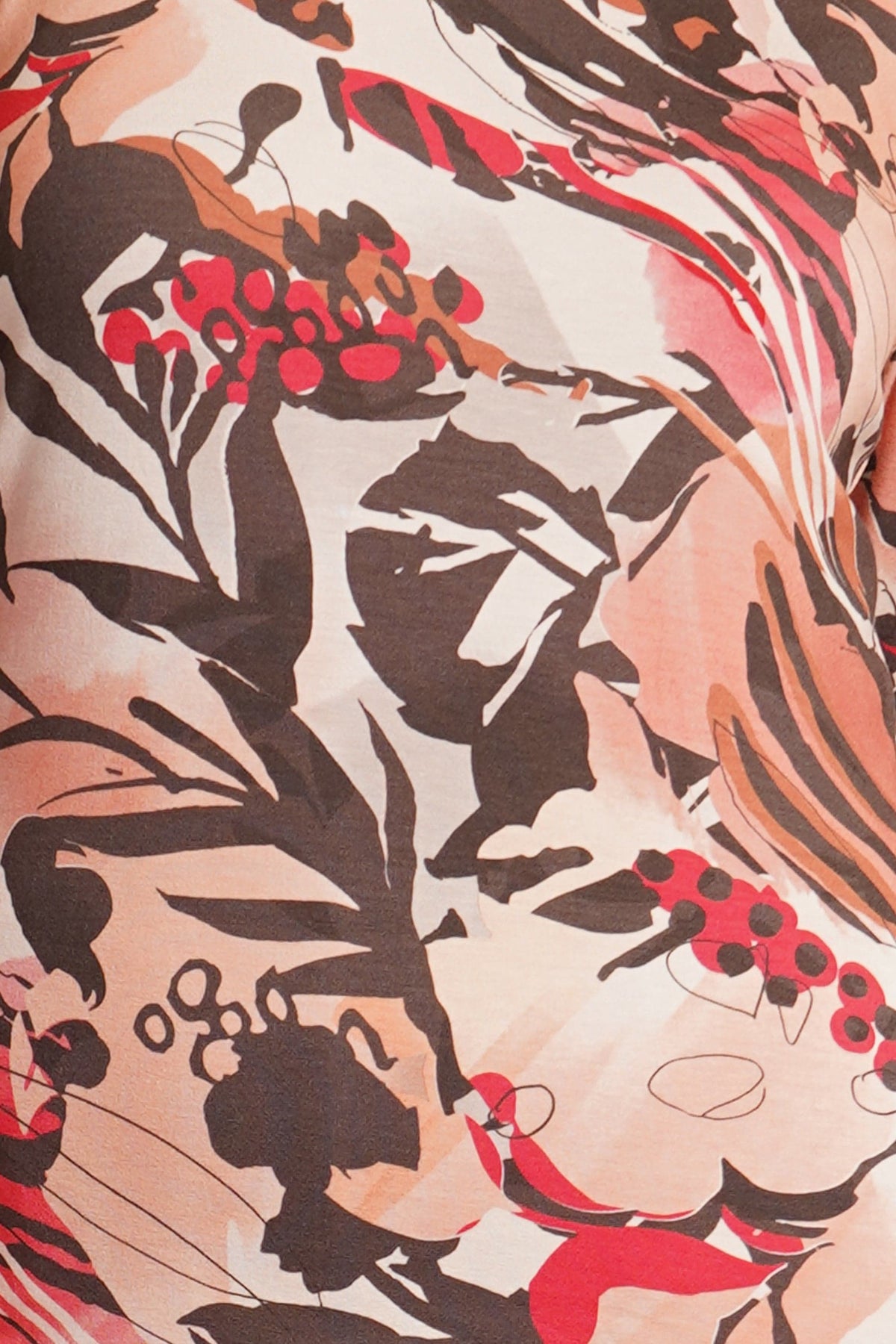 Kvinde sidder i en bluse med rund hals, 3/4 ærmer og grafisk blomsterprint til mørke bukser._3