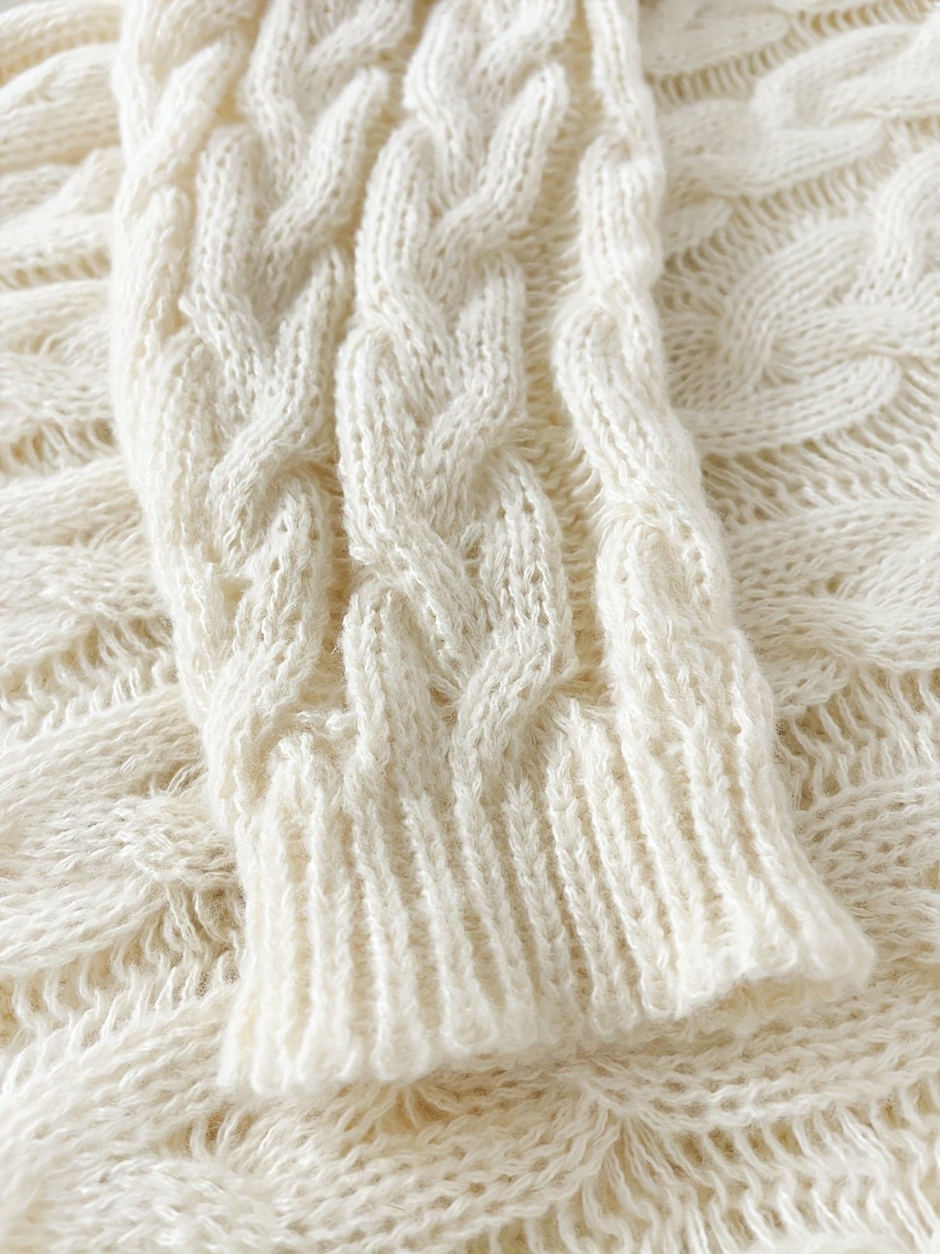 Kvinde iført en afslappet cable-knit sweater med v-hals og langt perlearmbånd_1
