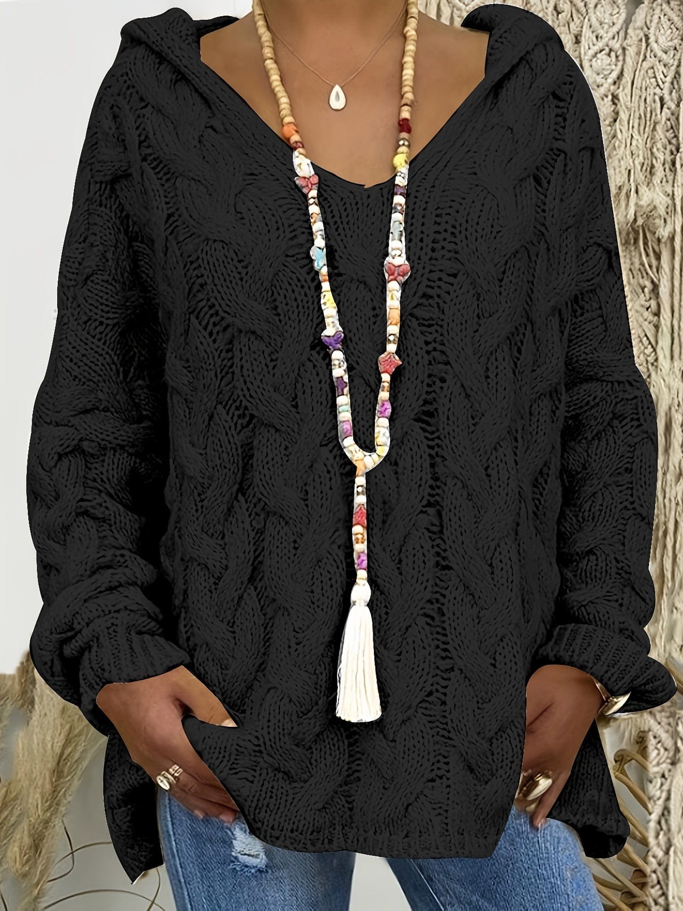 Kvinde iført en afslappet cable-knit sweater med v-hals og langt perlearmbånd_4