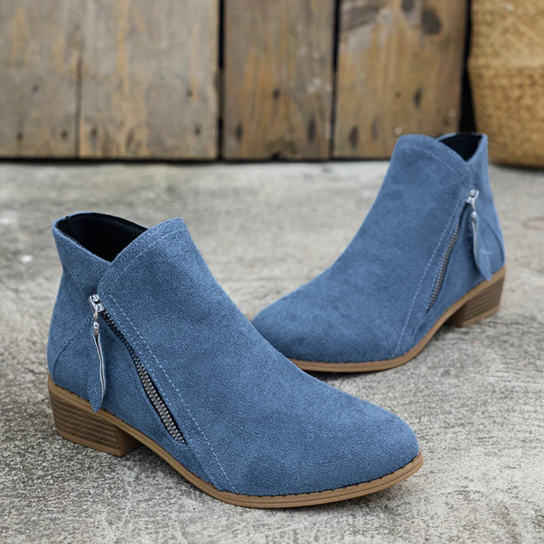 Ankelstøvler med blokhæl og lynlås i siden, vist sammen med jeans med slidsede detaljer ved anklerne._14