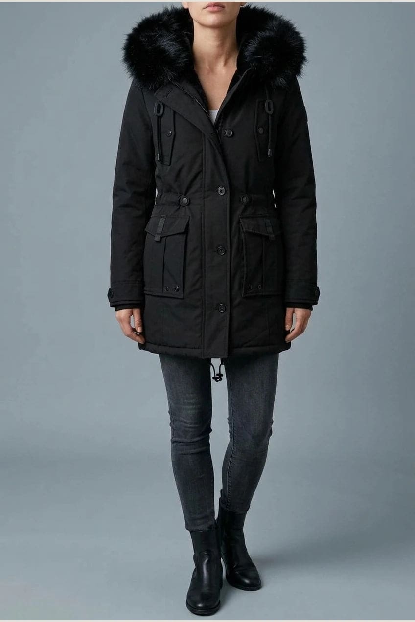Kvinde i lang vatteret parka med pelskant på hætten, knaprække, taljebånd og fire klaplommer, styles med jeans og støvler._0