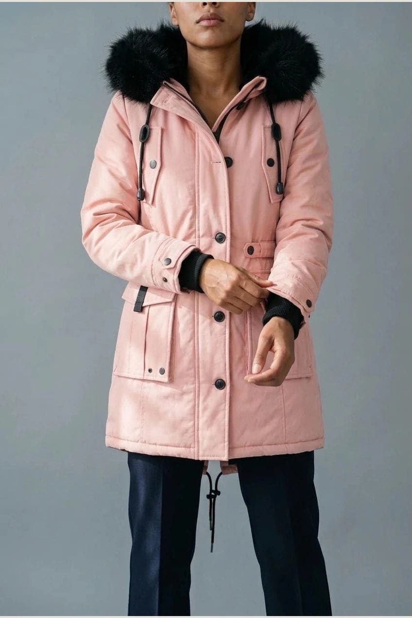 Kvinde i lang vatteret parka med pelskant på hætten, knaprække, taljebånd og fire klaplommer, styles med jeans og støvler._13
