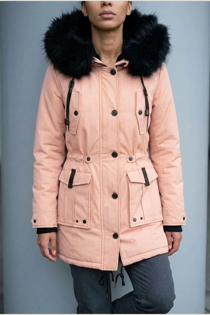 Kvinde i lang vatteret parka med pelskant på hætten, knaprække, taljebånd og fire klaplommer, styles med jeans og støvler._14