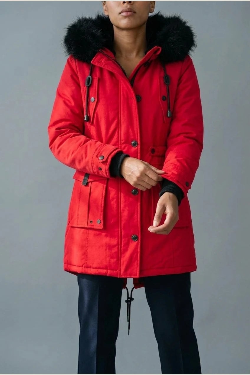 Kvinde i lang vatteret parka med pelskant på hætten, knaprække, taljebånd og fire klaplommer, styles med jeans og støvler._19