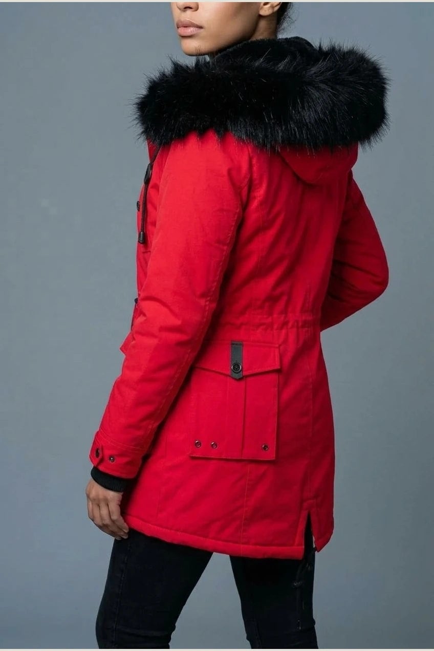 Kvinde i lang vatteret parka med pelskant på hætten, knaprække, taljebånd og fire klaplommer, styles med jeans og støvler._21