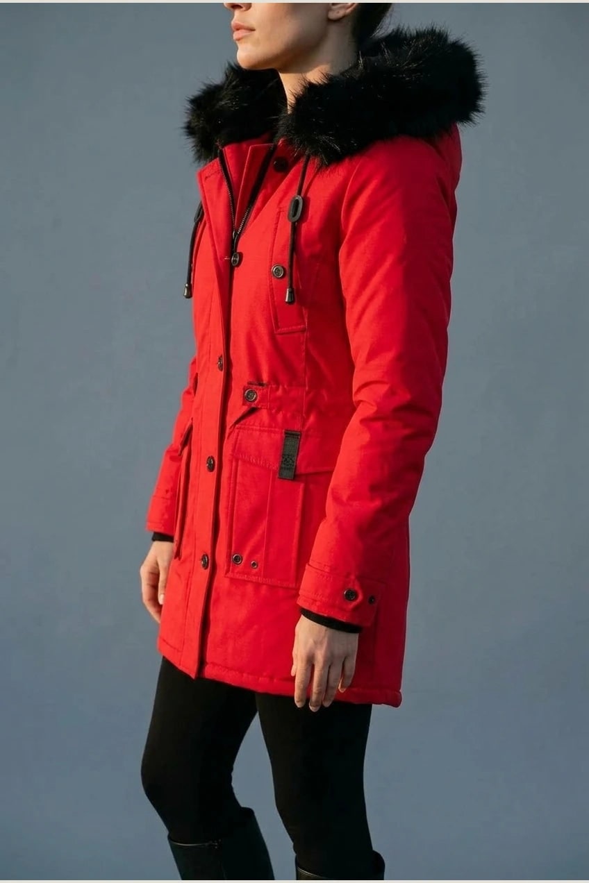 Kvinde i lang vatteret parka med pelskant på hætten, knaprække, taljebånd og fire klaplommer, styles med jeans og støvler._22