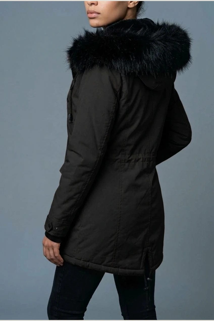 Kvinde i lang vatteret parka med pelskant på hætten, knaprække, taljebånd og fire klaplommer, styles med jeans og støvler._3