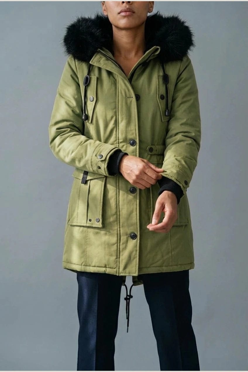 Kvinde i lang vatteret parka med pelskant på hætten, knaprække, taljebånd og fire klaplommer, styles med jeans og støvler._7