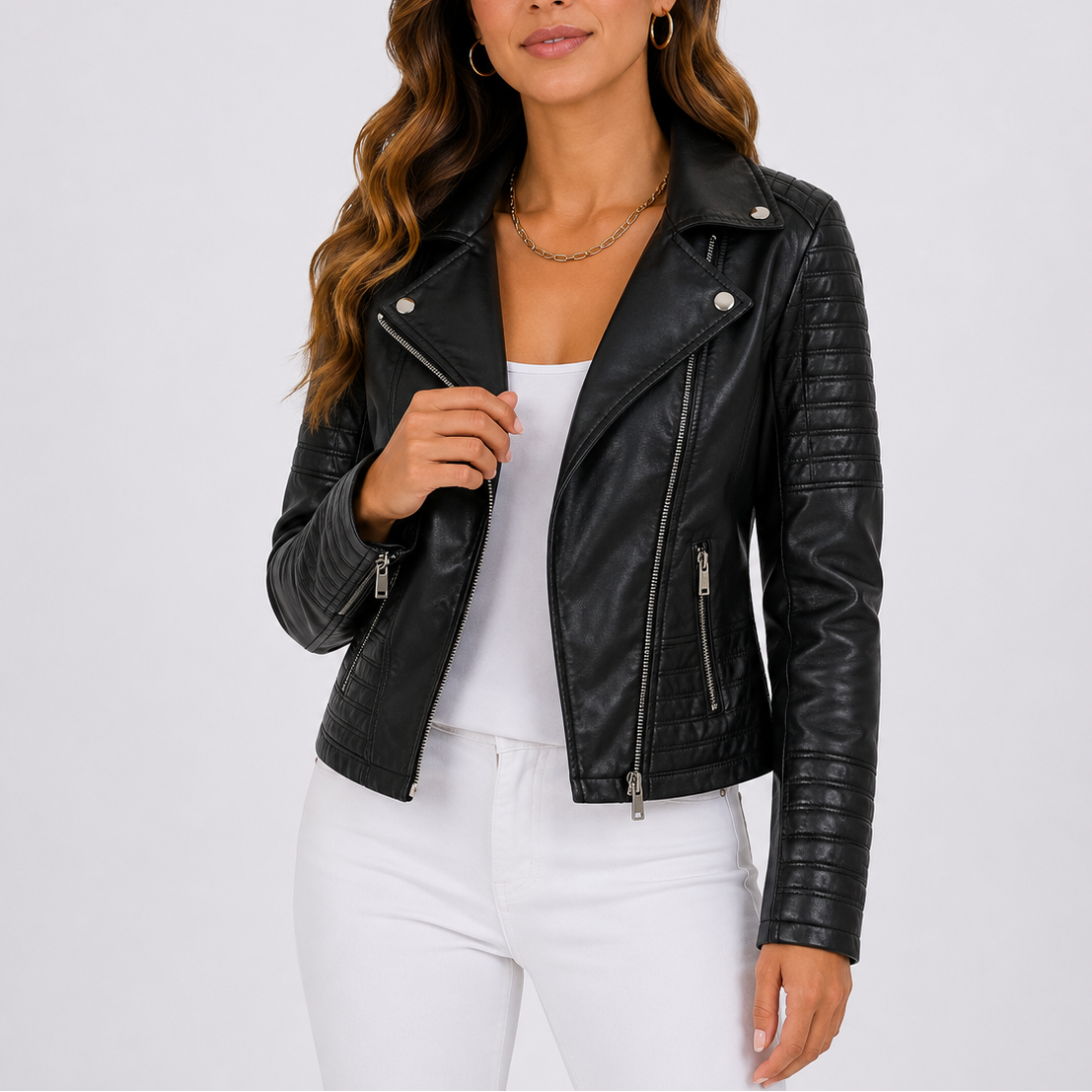 Kvinde iført sort bikerjakke med asymmetrisk lynlås, quiltede ærmer og revers, stylet med hvide jeans._0