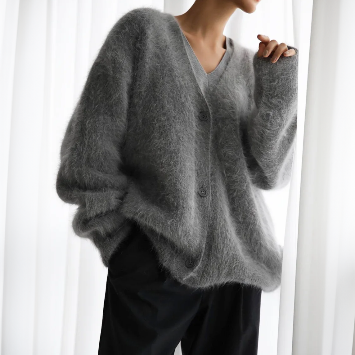Kvinde iført en lys beige oversize cardigan med knaplukning og v-hals, parret med lyse bukser._3