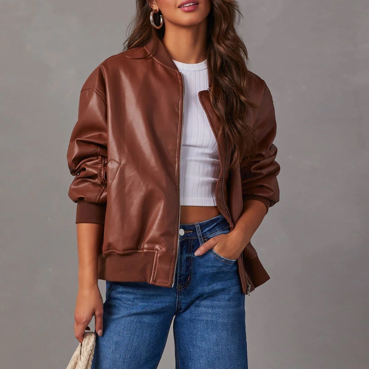 Kvinde iført brun bomber jakke med ribkanter og lynlås over hvid cropped top og jeans_0