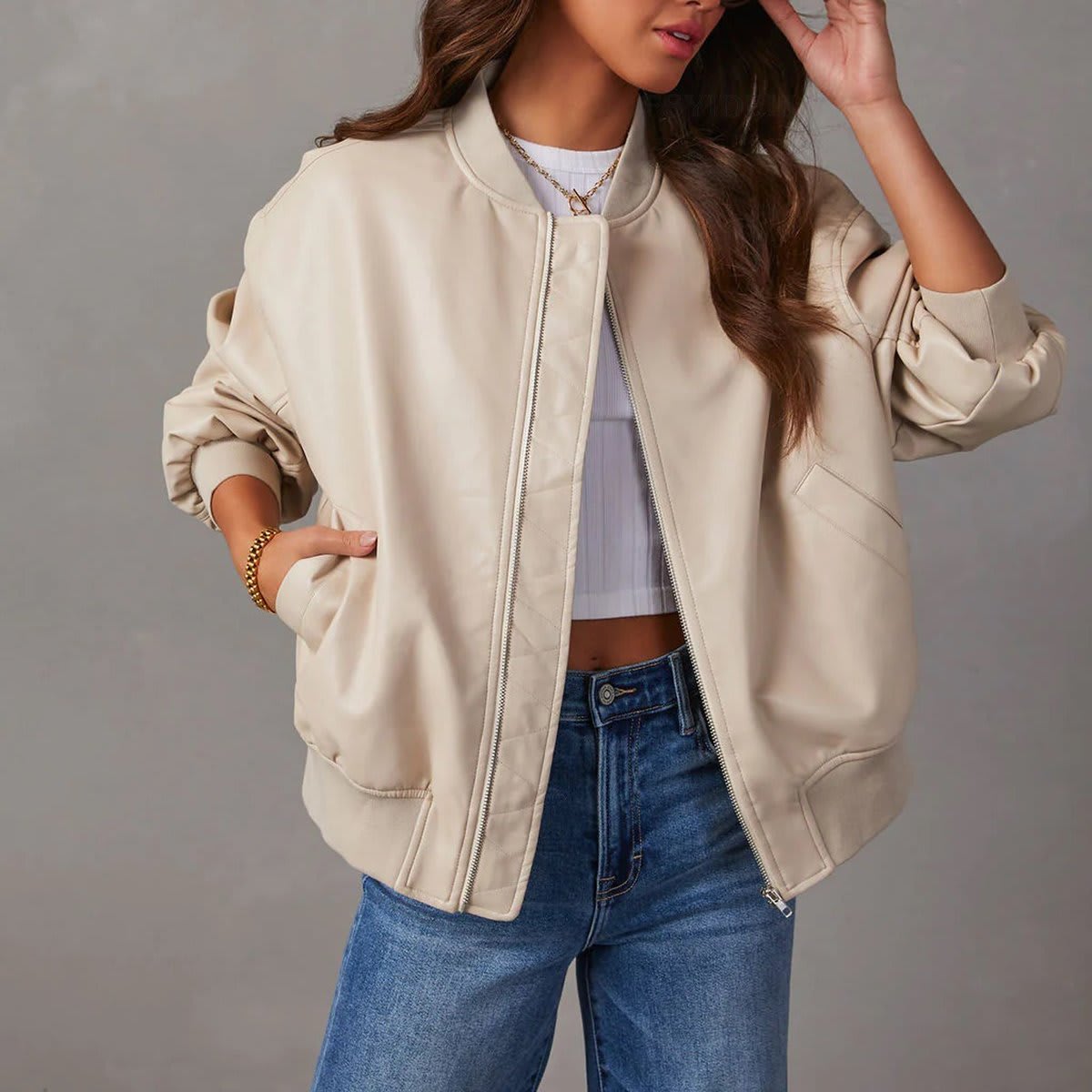 Kvinde iført brun bomber jakke med ribkanter og lynlås over hvid cropped top og jeans_1