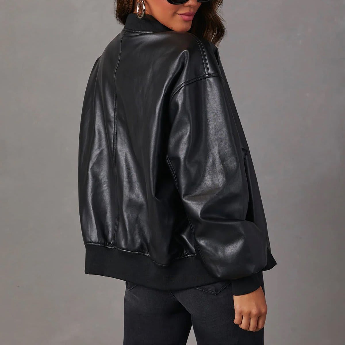Kvinde iført brun bomber jakke med ribkanter og lynlås over hvid cropped top og jeans_4