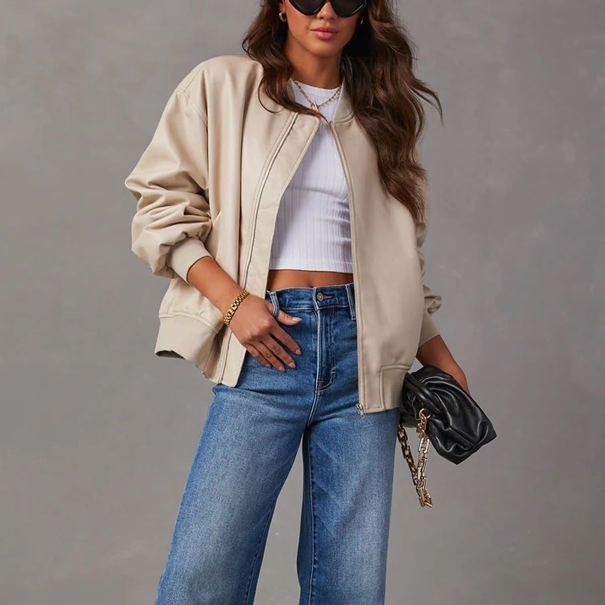 Kvinde iført brun bomber jakke med ribkanter og lynlås over hvid cropped top og jeans_5