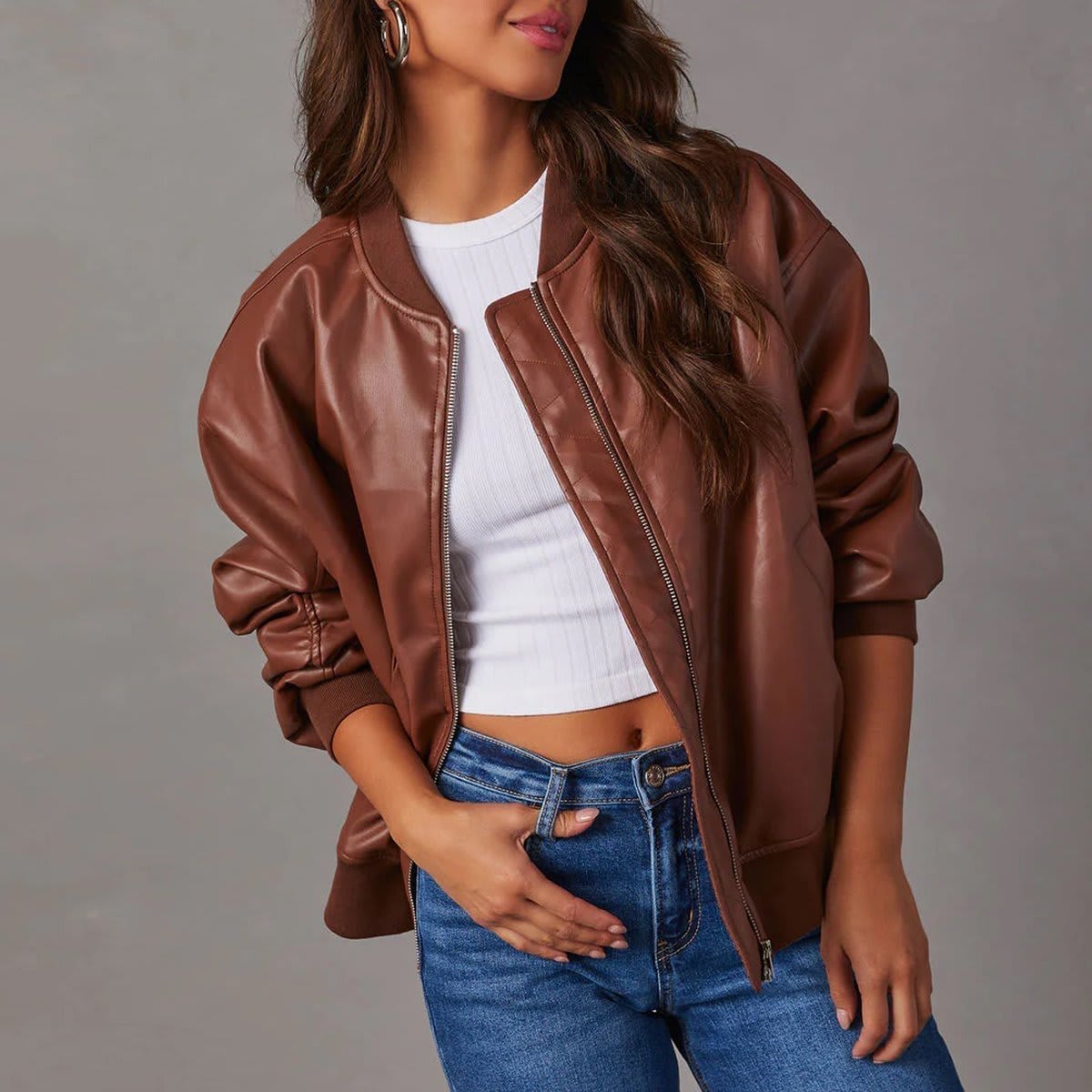 Kvinde iført brun bomber jakke med ribkanter og lynlås over hvid cropped top og jeans_6
