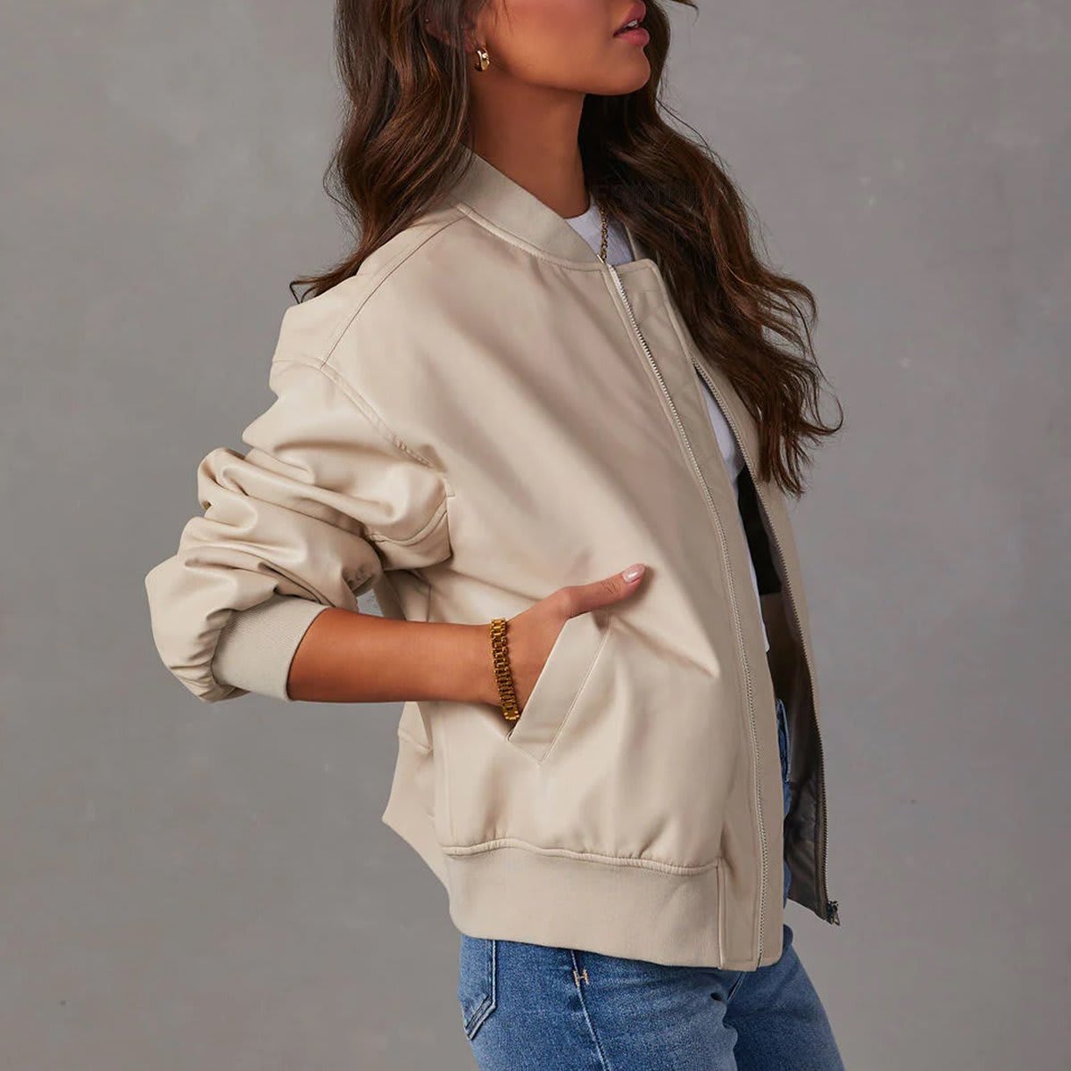 Kvinde iført brun bomber jakke med ribkanter og lynlås over hvid cropped top og jeans_7