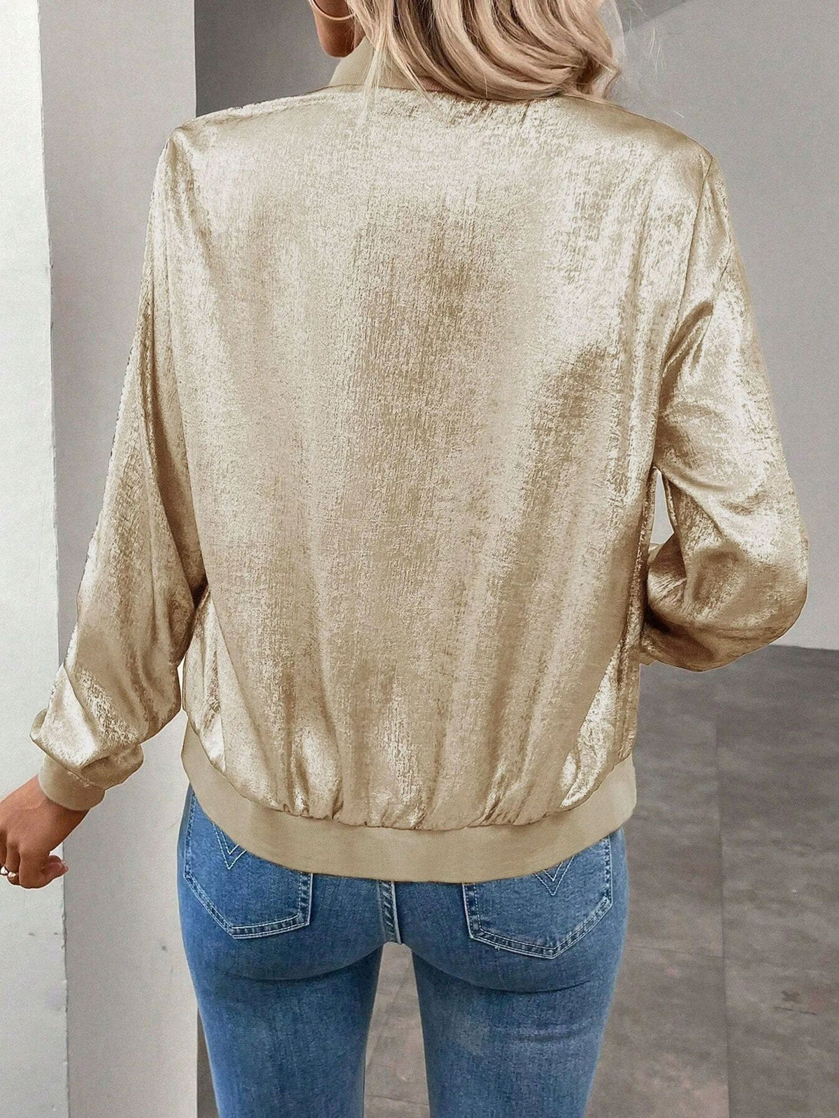 Kvinde iført kort bomber jakke med shimmer-finish og lynlås foran, stylet med hvid top og jeans_1
