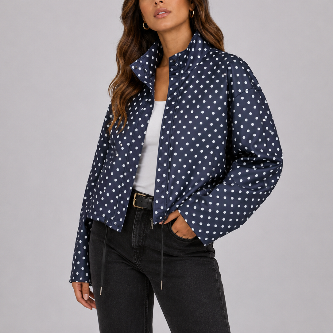 Kvinde iført en prikket bomber jakke med lynlås og ståkrave, stylet med hvid top og mørke jeans._0