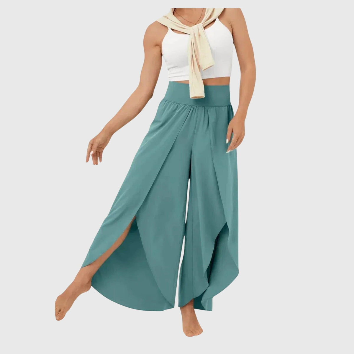 Kvinde iført en hvid crop top og luftige, brede bukser i jadegrøn med dekorative slidser og flydende vidt snit._0
