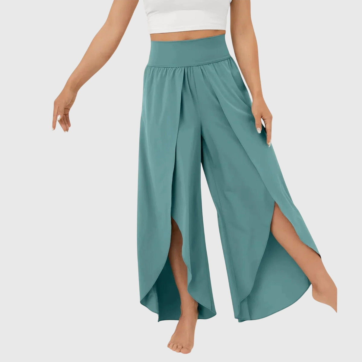 Kvinde iført en hvid crop top og luftige, brede bukser i jadegrøn med dekorative slidser og flydende vidt snit._1