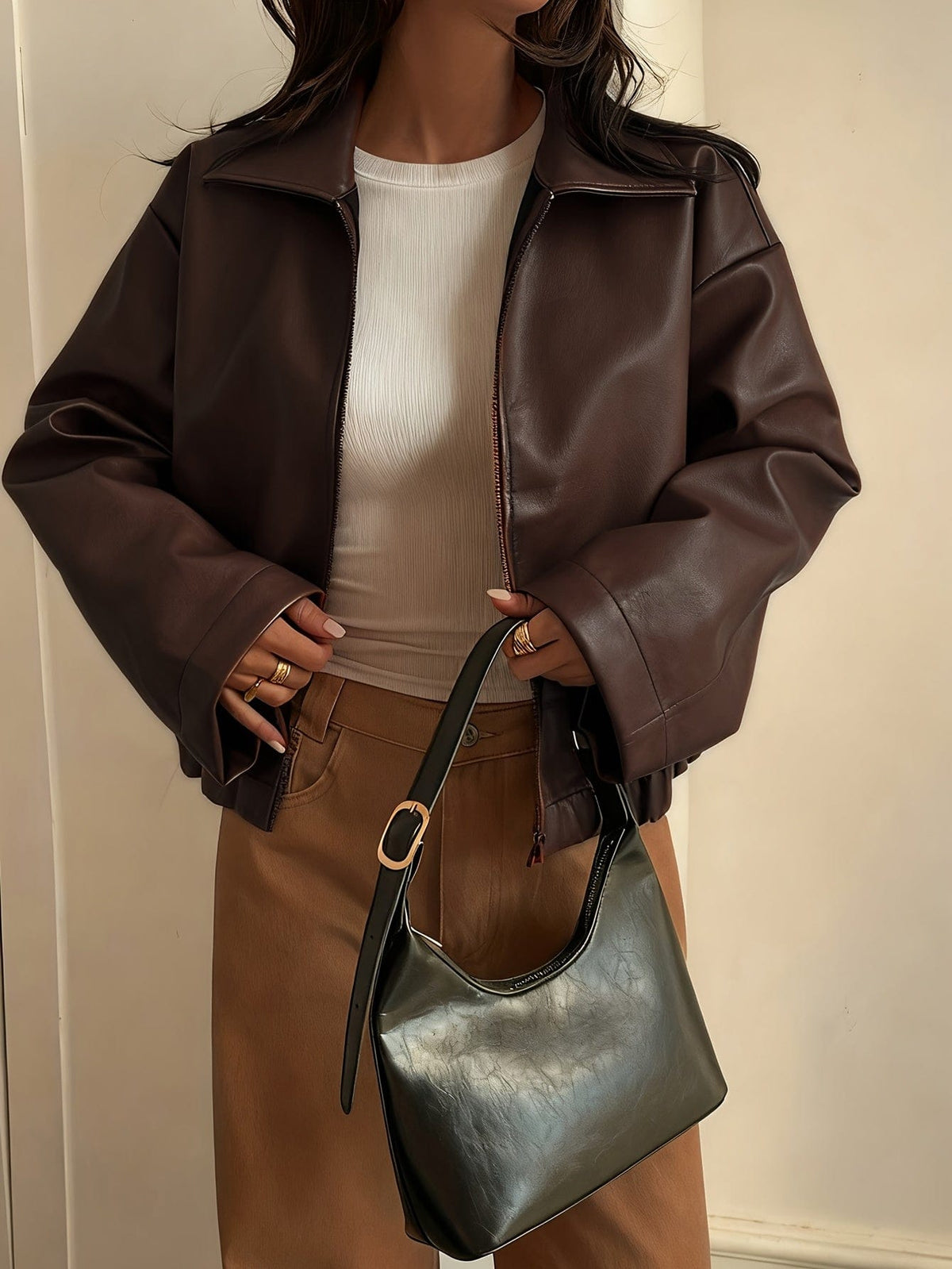 Kvinde iført brun cropped jakke med krave og lynlås, stylet med hvid striktrøje og beige bukser_3