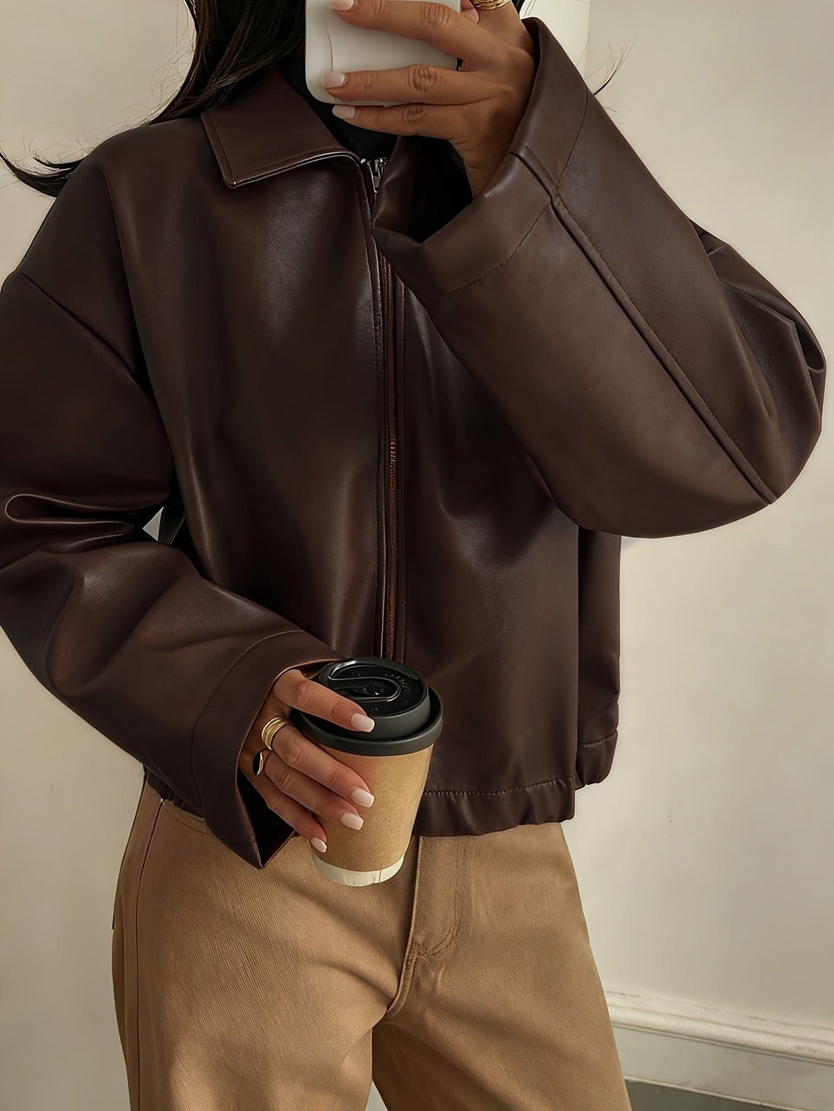 Kvinde iført brun cropped jakke med krave og lynlås, stylet med hvid striktrøje og beige bukser_5