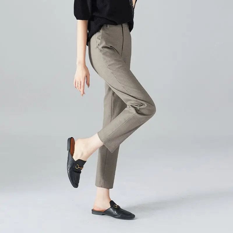 Kvinde iført sorte loafers, grå bukser med høj talje og sort cardigan i neutral kulisse._11