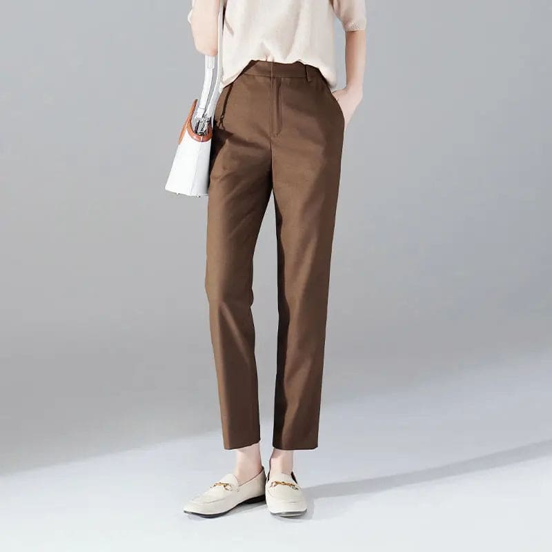 Kvinde iført sorte loafers, grå bukser med høj talje og sort cardigan i neutral kulisse._12