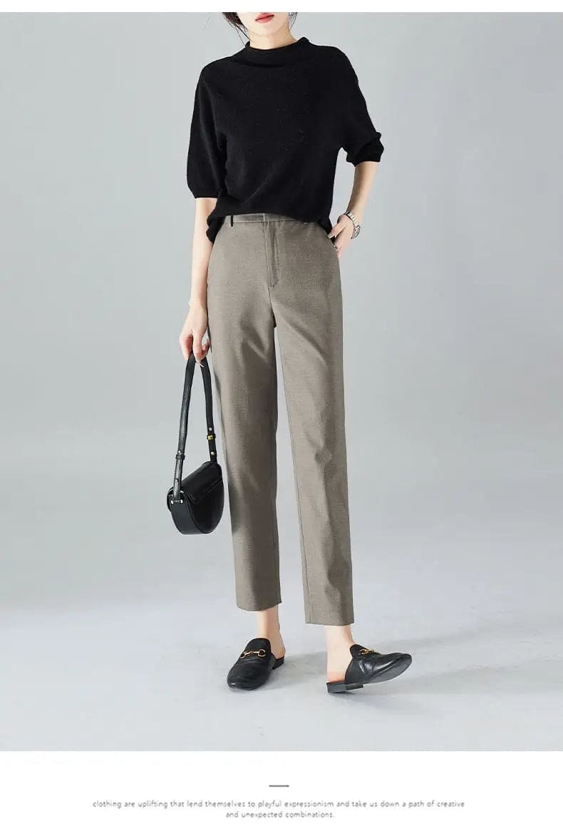 Kvinde iført sorte loafers, grå bukser med høj talje og sort cardigan i neutral kulisse._14