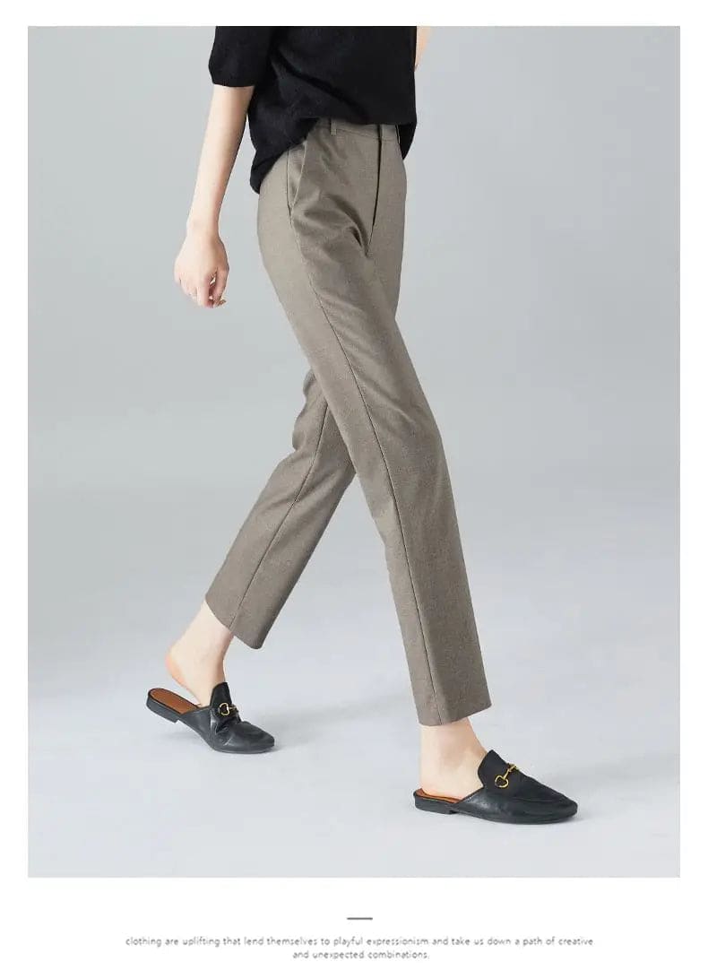Kvinde iført sorte loafers, grå bukser med høj talje og sort cardigan i neutral kulisse._15