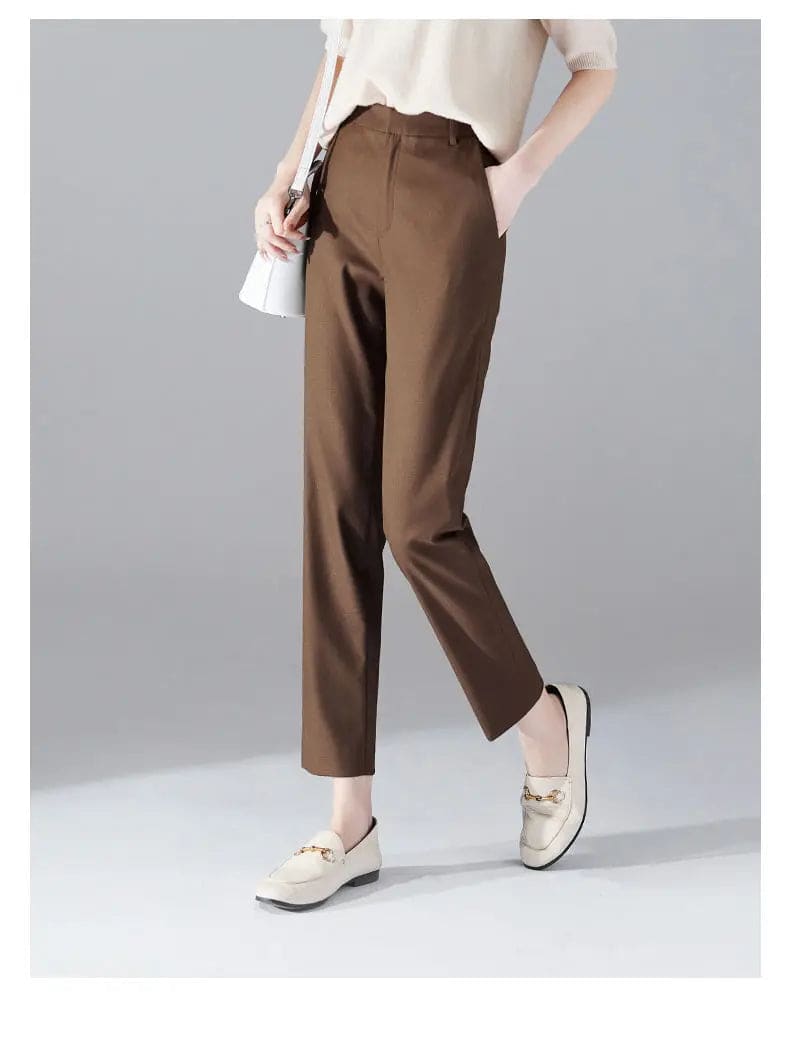Kvinde iført sorte loafers, grå bukser med høj talje og sort cardigan i neutral kulisse._19