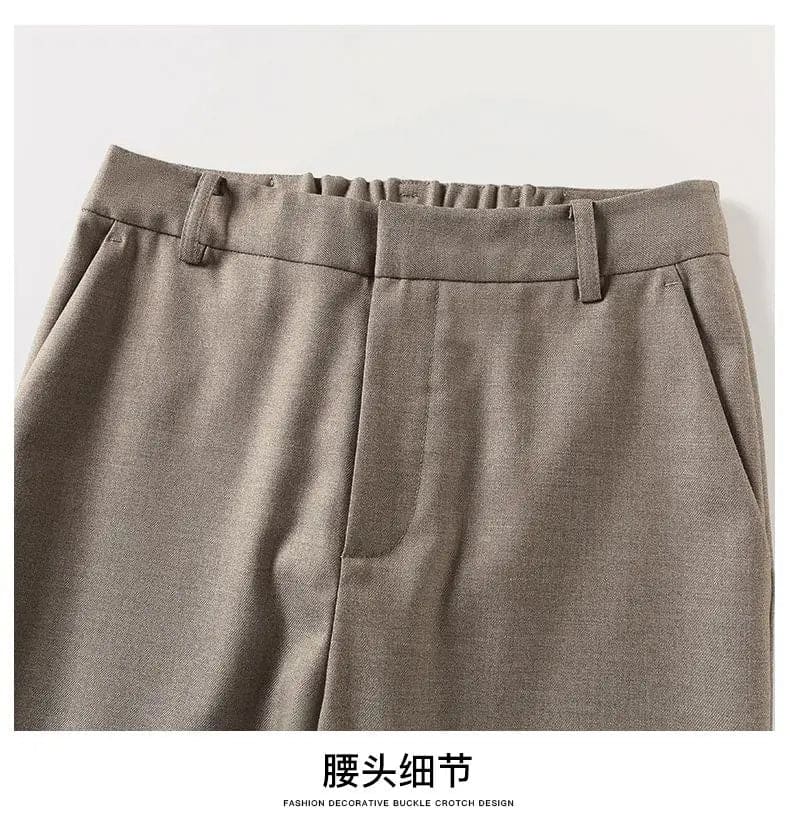 Kvinde iført sorte loafers, grå bukser med høj talje og sort cardigan i neutral kulisse._20
