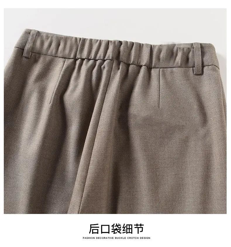Kvinde iført sorte loafers, grå bukser med høj talje og sort cardigan i neutral kulisse._22