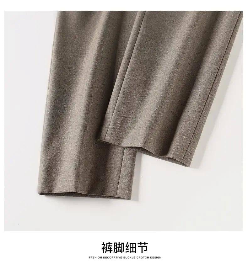 Kvinde iført sorte loafers, grå bukser med høj talje og sort cardigan i neutral kulisse._23