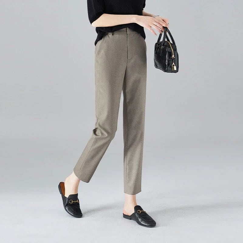 Kvinde iført sorte loafers, grå bukser med høj talje og sort cardigan i neutral kulisse._7