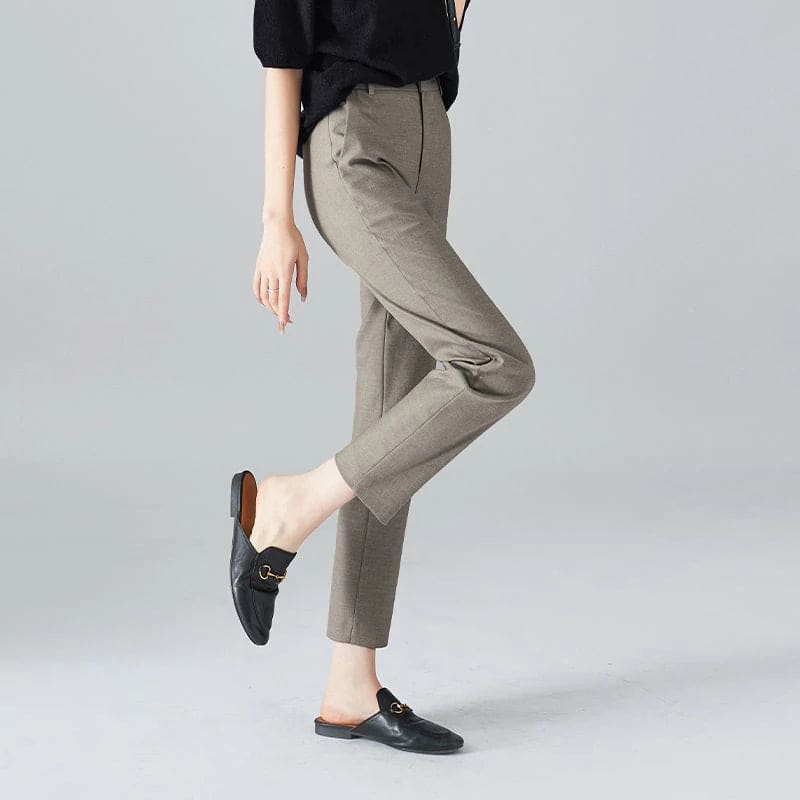 Kvinde iført sorte loafers, grå bukser med høj talje og sort cardigan i neutral kulisse._8