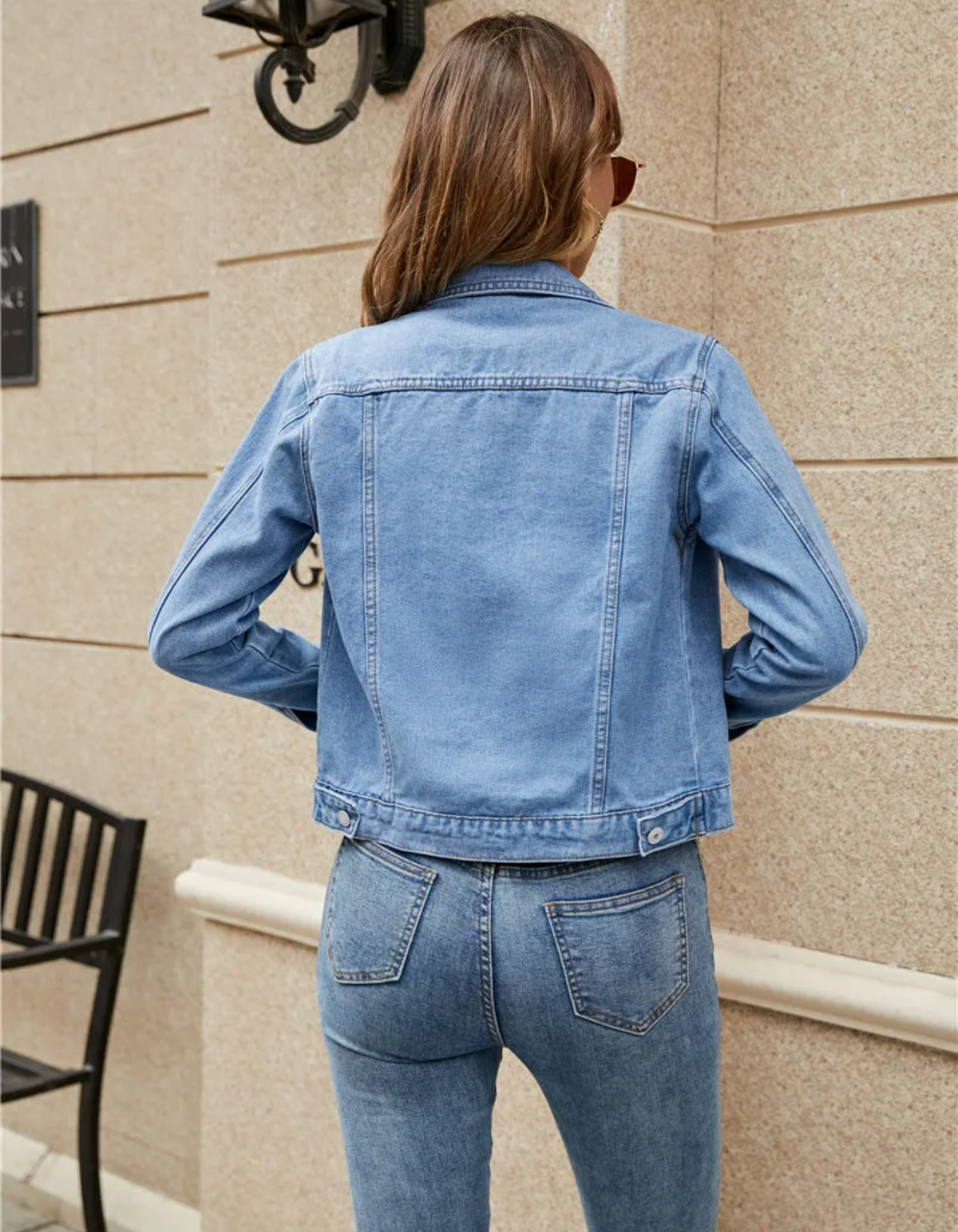 Kort denimjakke med skjortekrave, knaplukning foran og to brystlommer med klap, båret åben over en hvid t-shirt og jeans._3