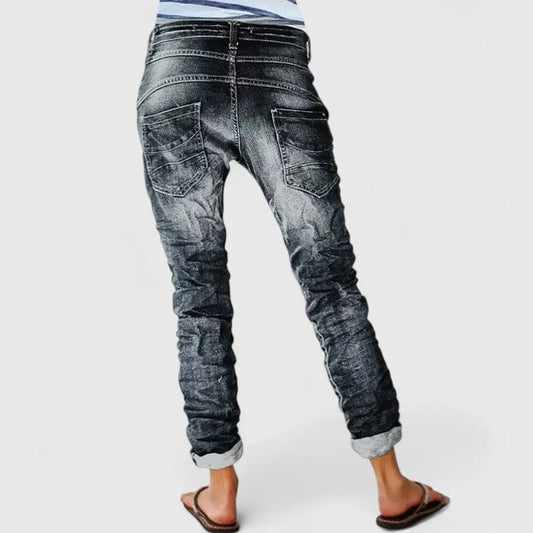 Kvinde set bagfra iført mørke denimbukser med distressed finish og opsmøgede bukseben._0
