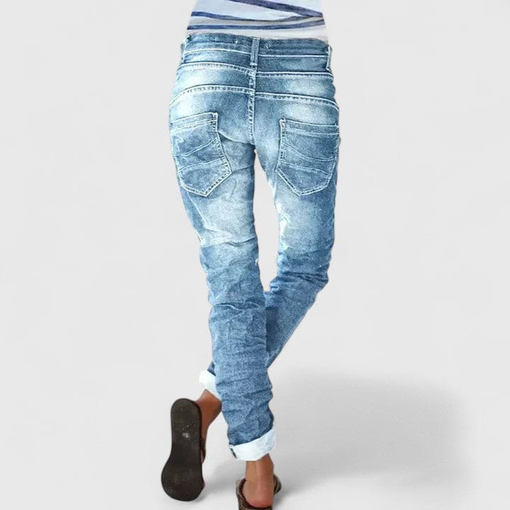 Kvinde set bagfra iført mørke denimbukser med distressed finish og opsmøgede bukseben._1