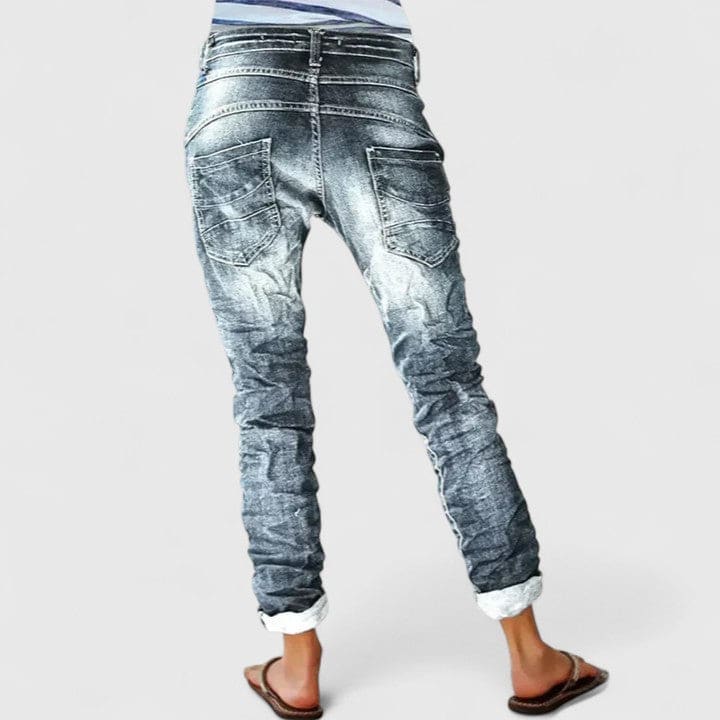 Kvinde set bagfra iført mørke denimbukser med distressed finish og opsmøgede bukseben._2