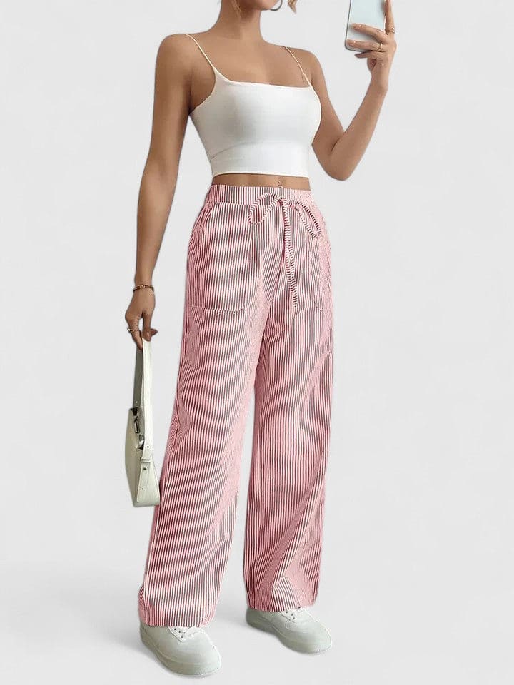 Dame iført vidbenede bukser med blå og hvide striber og elastik i taljen samt hvide sneakers_11
