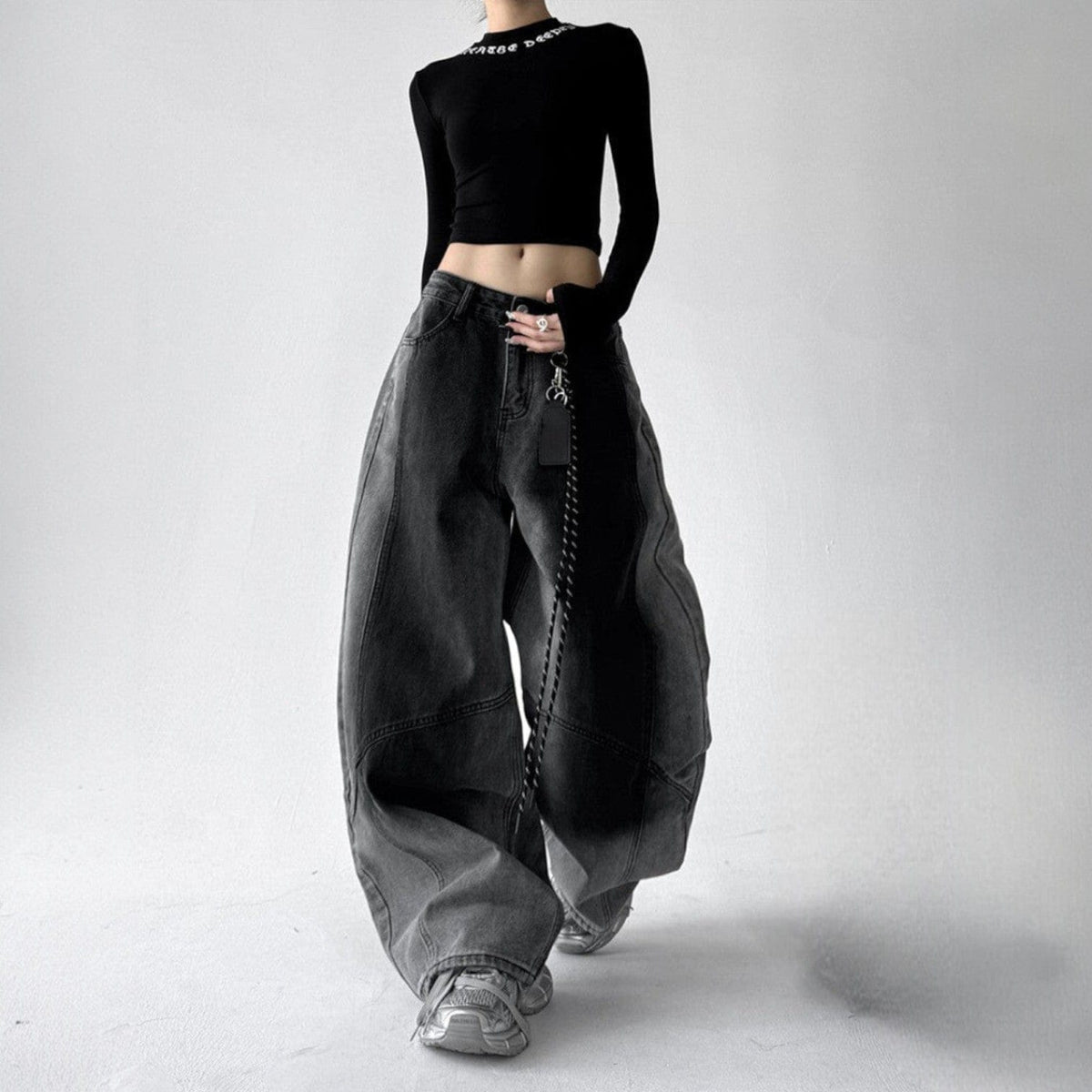 Model iført jeans med ekstra vide ben, buede sømme og en kædedetalje ved hoften._6