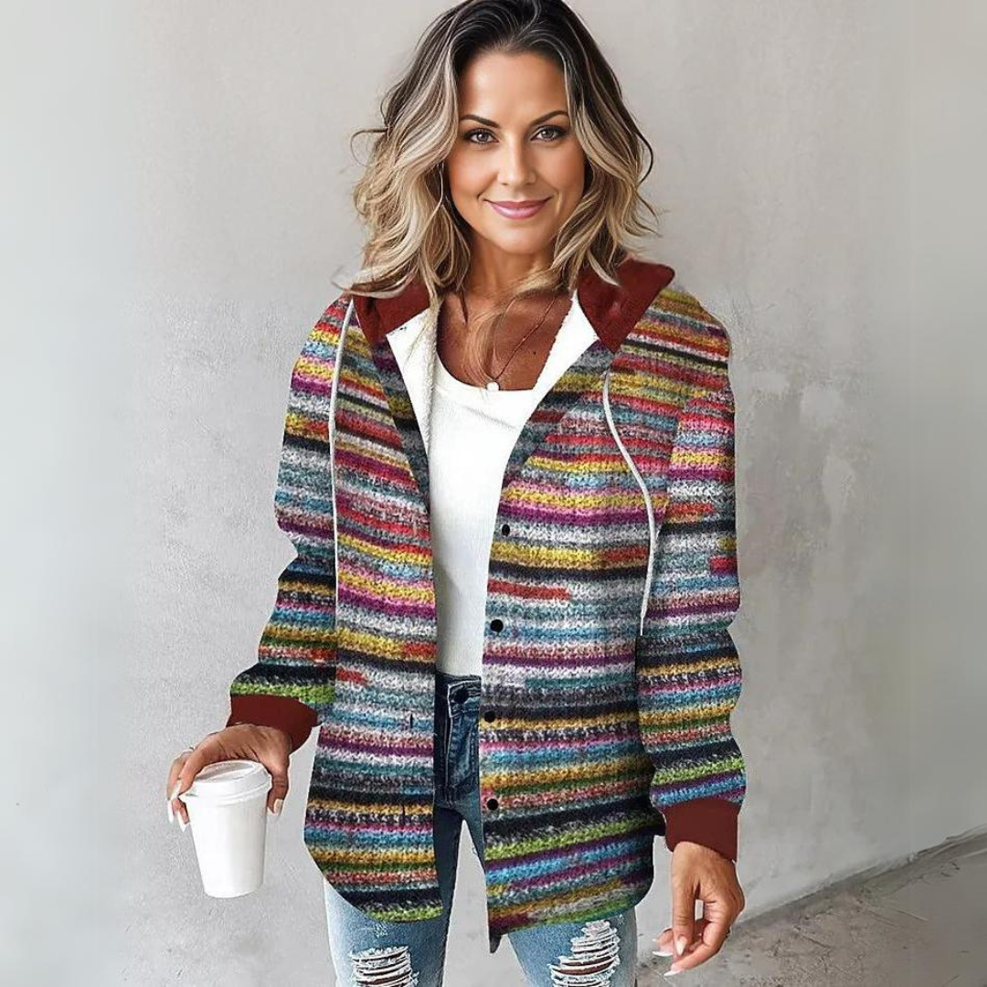 Kvinde iført farverig strikket cardigan med striber, hætte og lommer over hvid top og jeans_1