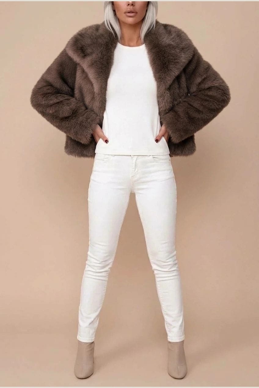 Kort jakke i fake fur med stor krave, åben front og voluminøse ærmer, båret over en enkel top og smalle bukser._1