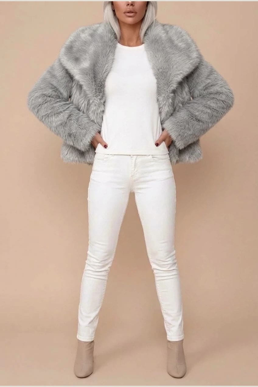 Kort jakke i fake fur med stor krave, åben front og voluminøse ærmer, båret over en enkel top og smalle bukser._7