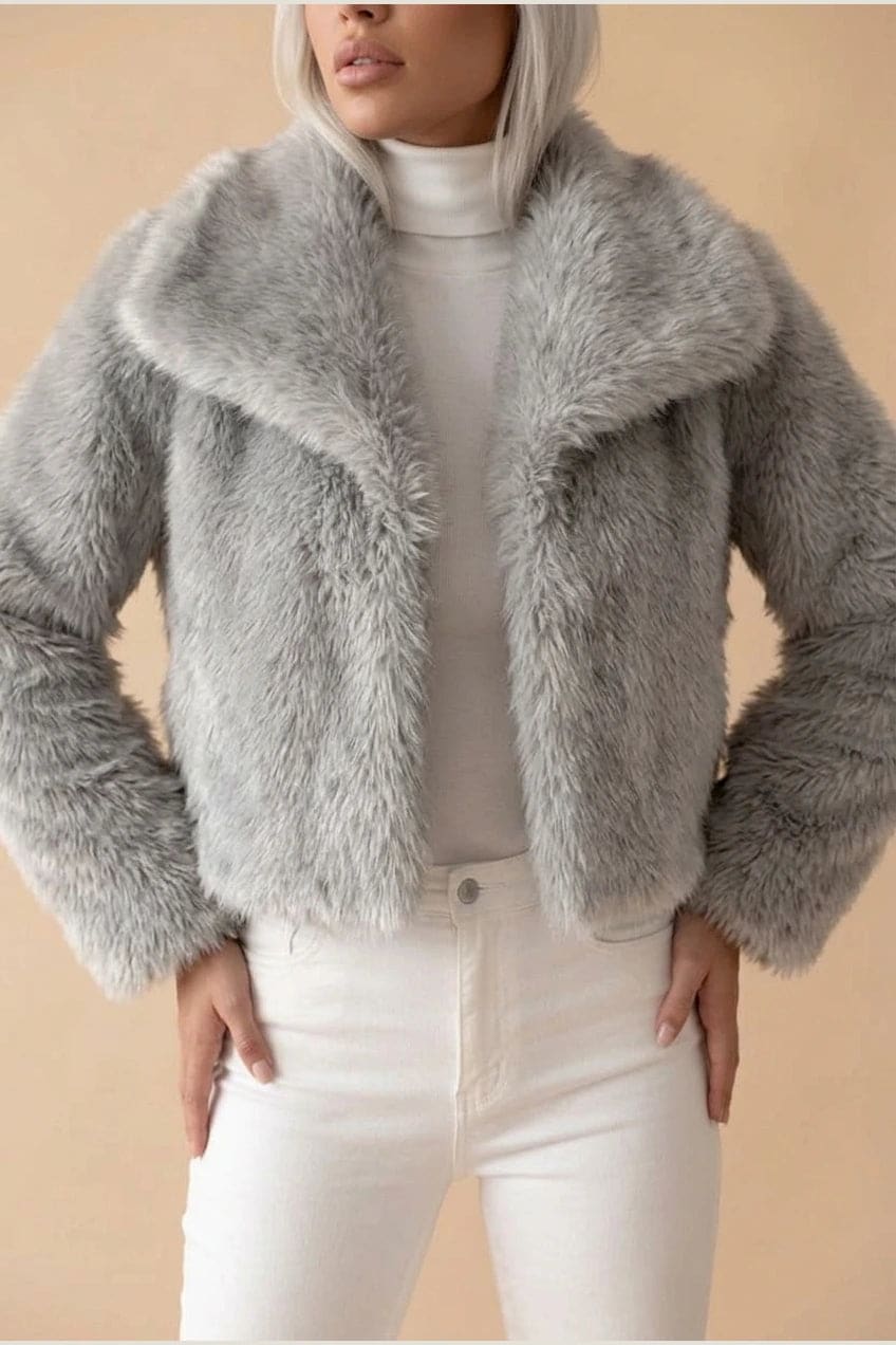Kort jakke i fake fur med stor krave, åben front og voluminøse ærmer, båret over en enkel top og smalle bukser._8