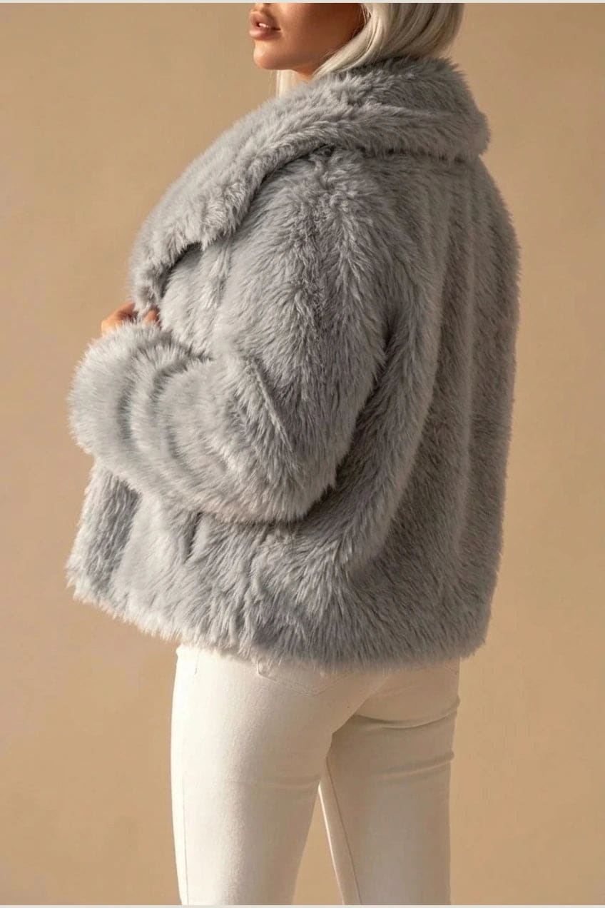 Kort jakke i fake fur med stor krave, åben front og voluminøse ærmer, båret over en enkel top og smalle bukser._9