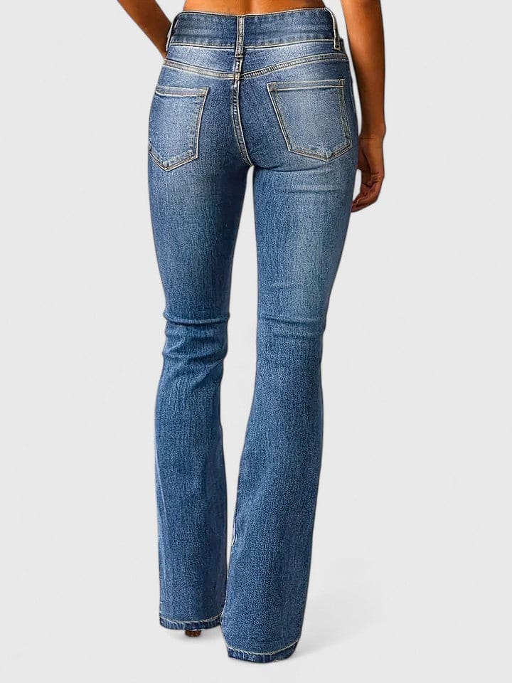 Kvinde iført flared jeans med høj talje og dobbelt knaplukning i mellemblå vask, stylet med nude crop top og brune støvletter._3