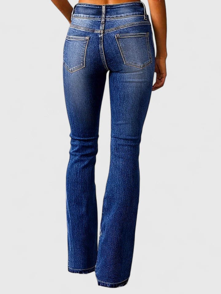 Kvinde iført flared jeans med høj talje og dobbelt knaplukning i mellemblå vask, stylet med nude crop top og brune støvletter._4