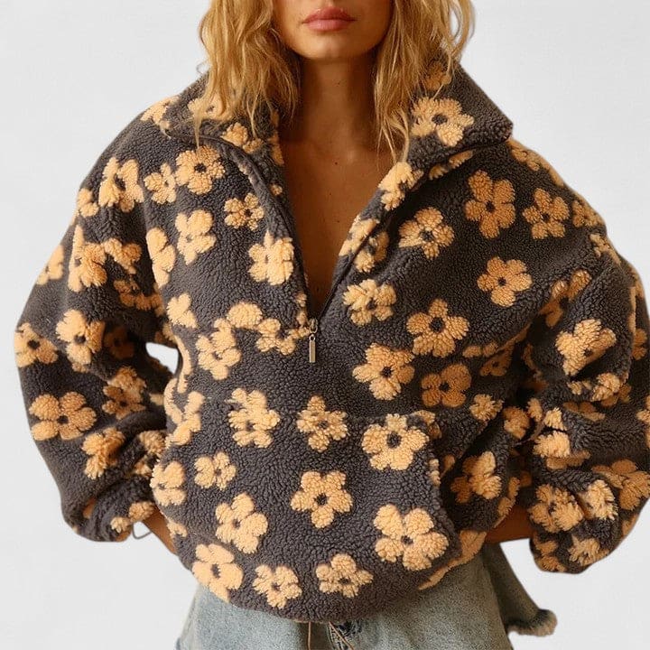 Kvinde iført en fleece sweater med blomstermønster og halv lynlås foran, fotograferet mod lys baggrund._0